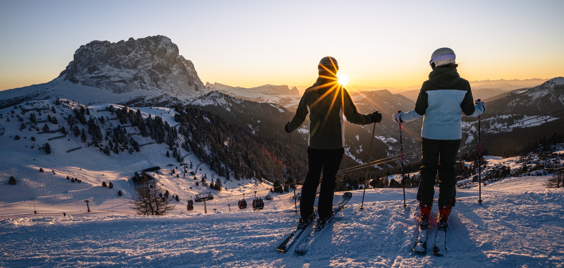 Two skiers watching the sun set over the Dolomites