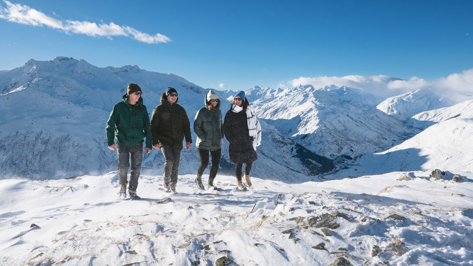 Four friends on a winter walk along a snowy ridge at Gütsch, high above the Urseren Valley