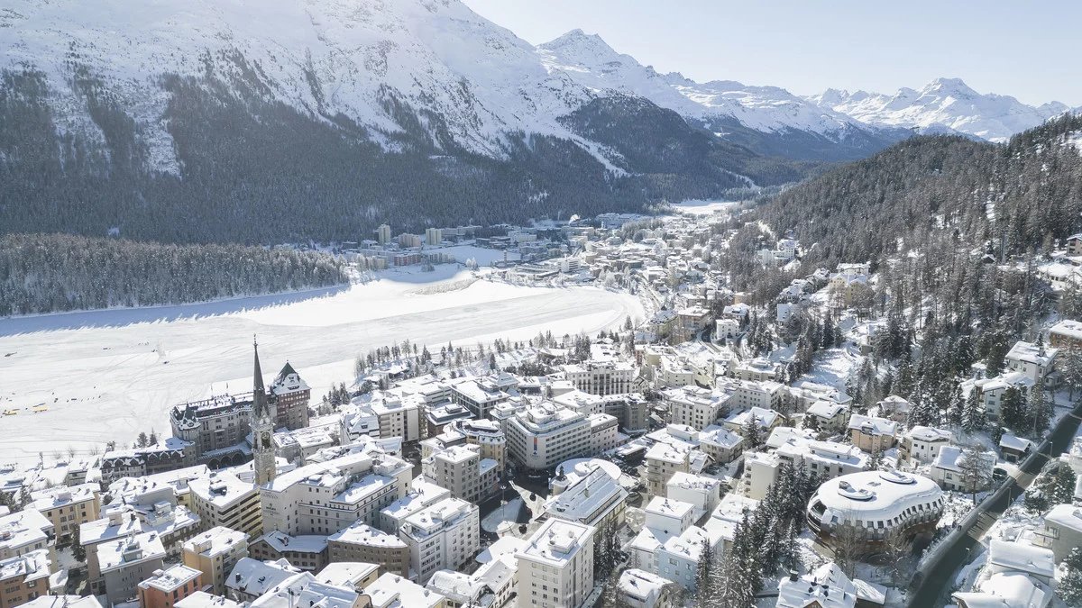 St. Moritz and its leaning tower above the frozen lake, framed by snowy mountains