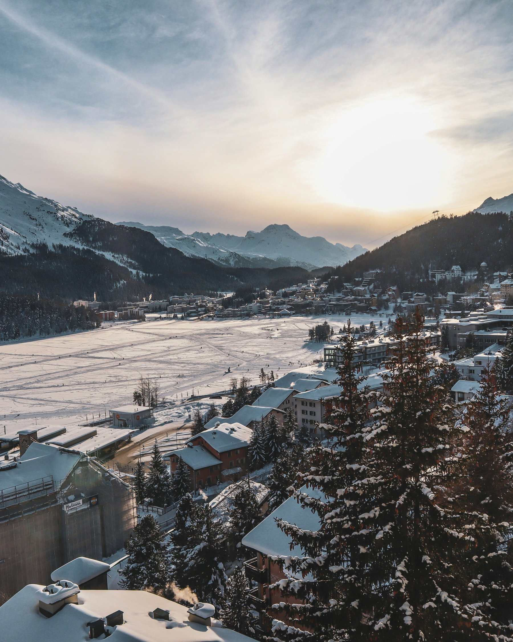 The sun setting over the frozen lake and the snowy Engadin valley at St. Moritz