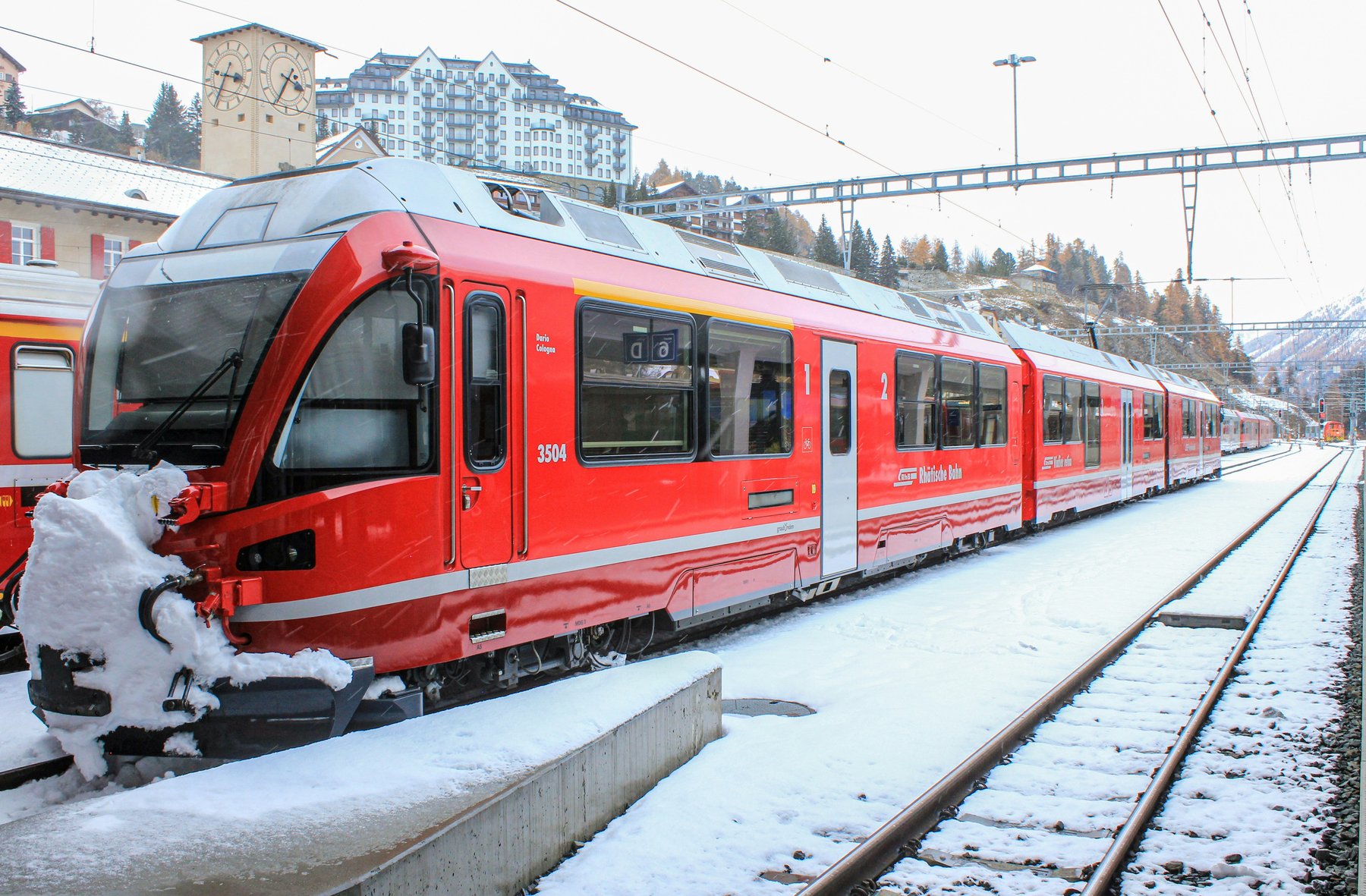 A red Rhaetian Railway train waiting at snowy St. Moritz station