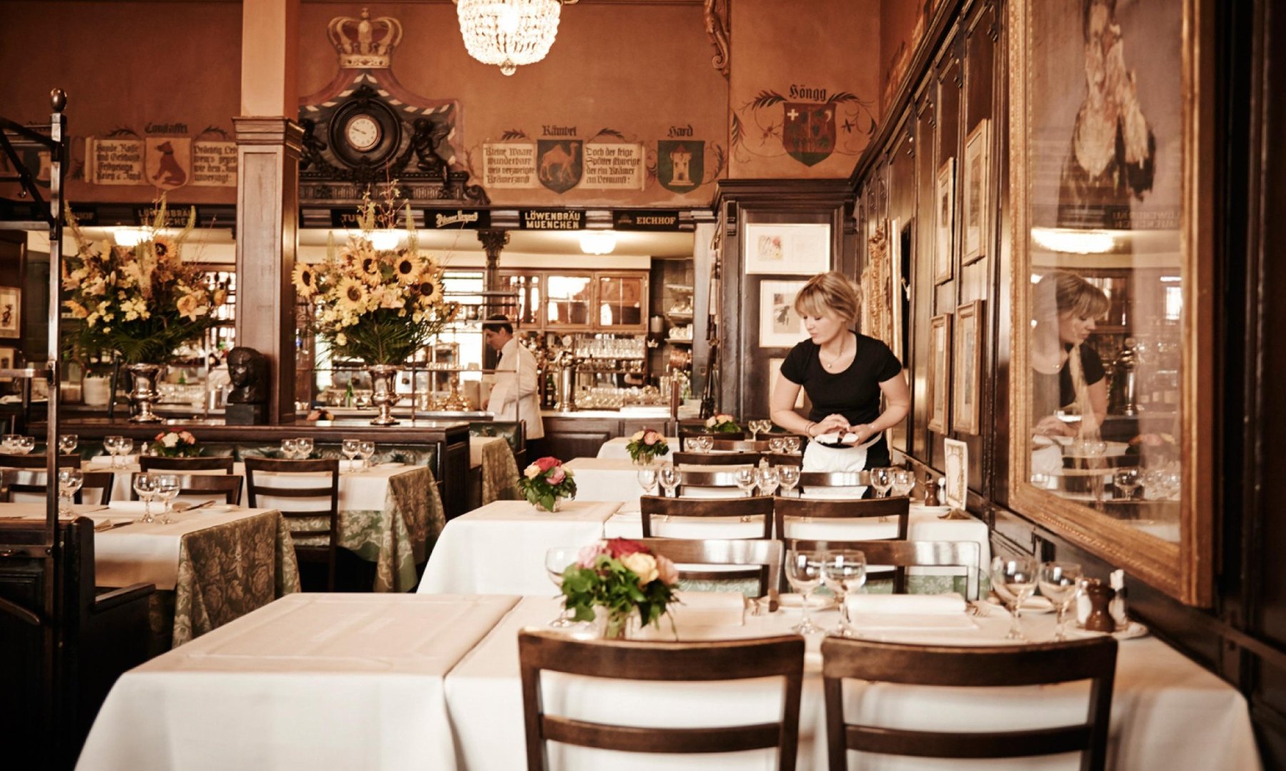 Kronenhalle's dining room, with white tablecloths, guild crests and framed art on the walls