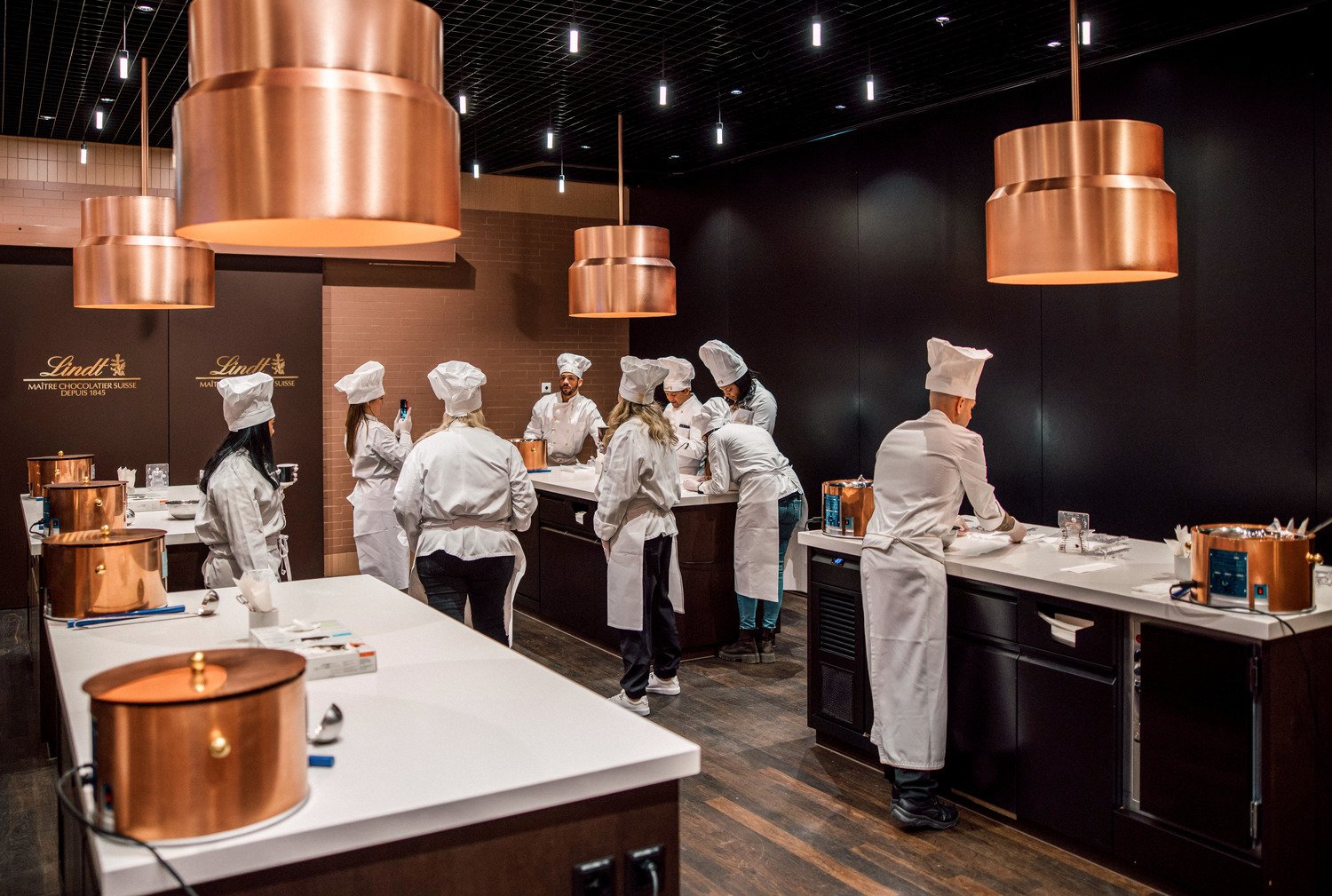 Guests in chef's whites making chocolate at Lindt Home of Chocolate
