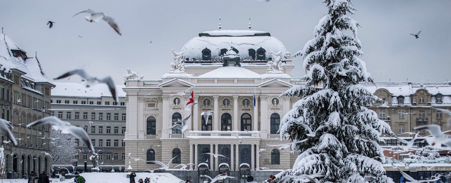 The Zurich Opera House behind a snow-covered square and a Christmas tree