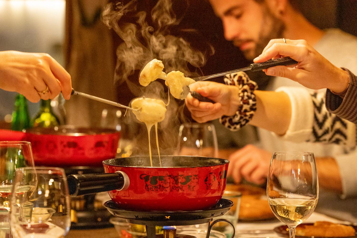 Friends dipping bread into a pot of melted cheese fondue