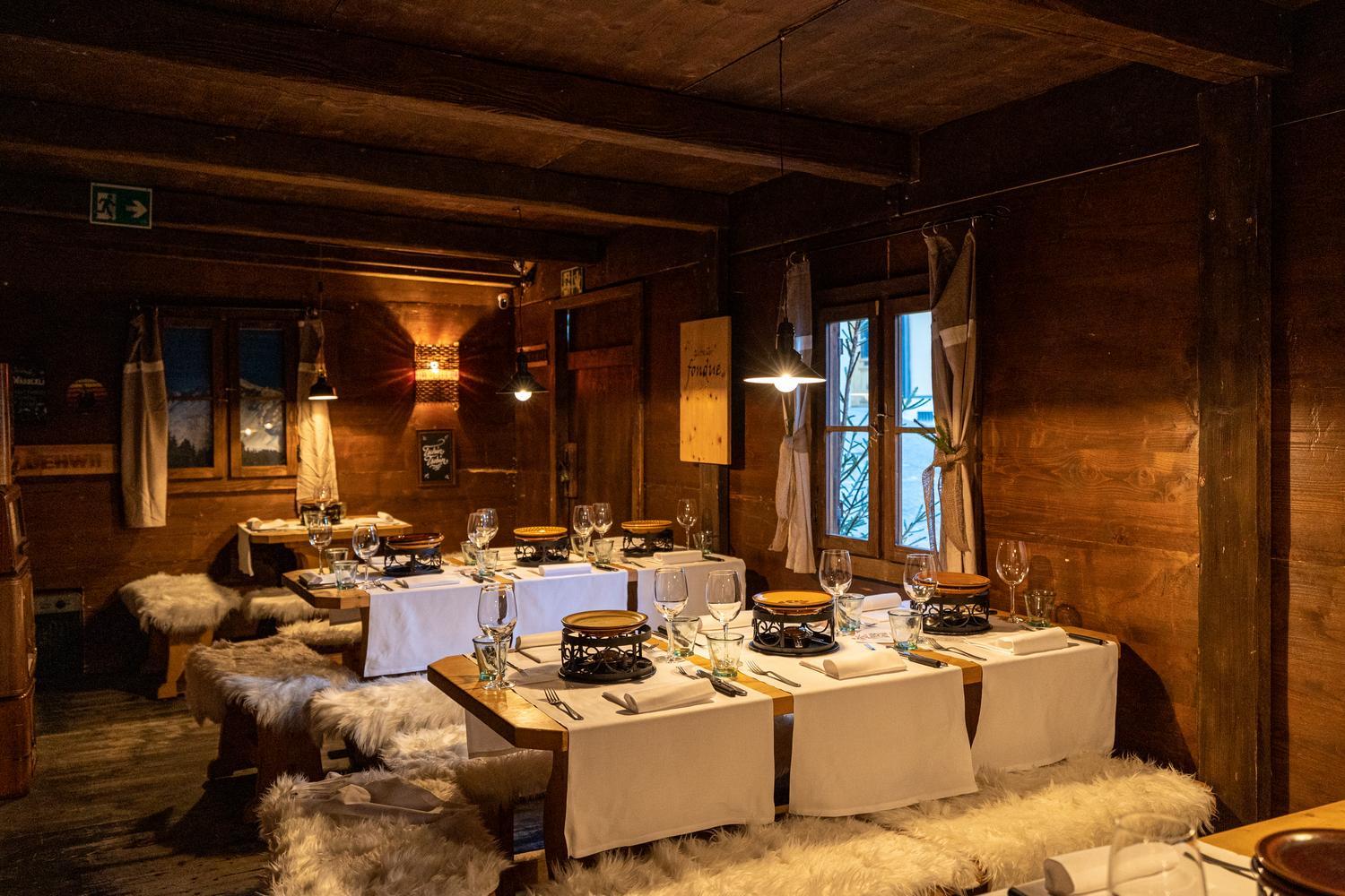 A wood-paneled fondue cellar set with cheese pots and wine glasses