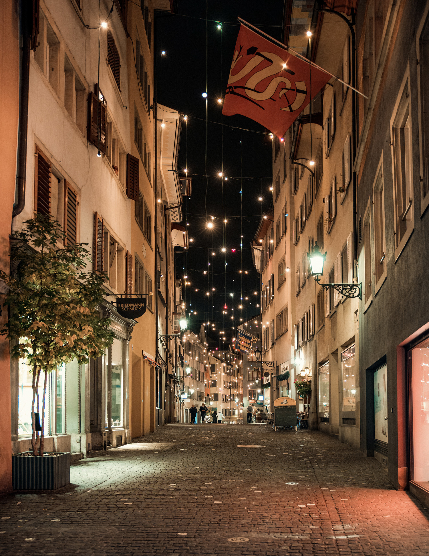 A cobblestone Old Town lane strung with lights at night