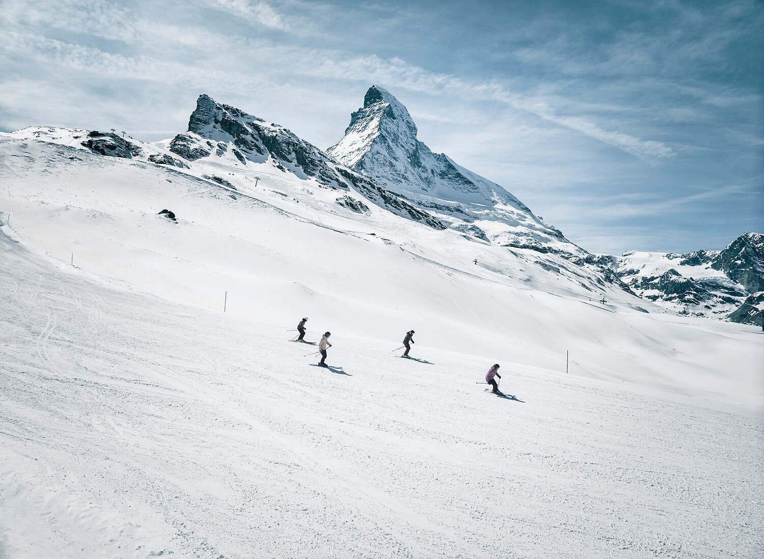 A group of skiers carving turns with the Matterhorn behind