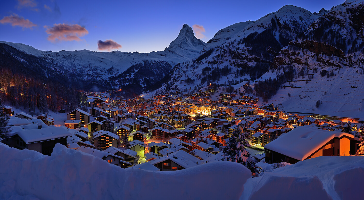 Zermatt village lit up at dusk beneath the Matterhorn