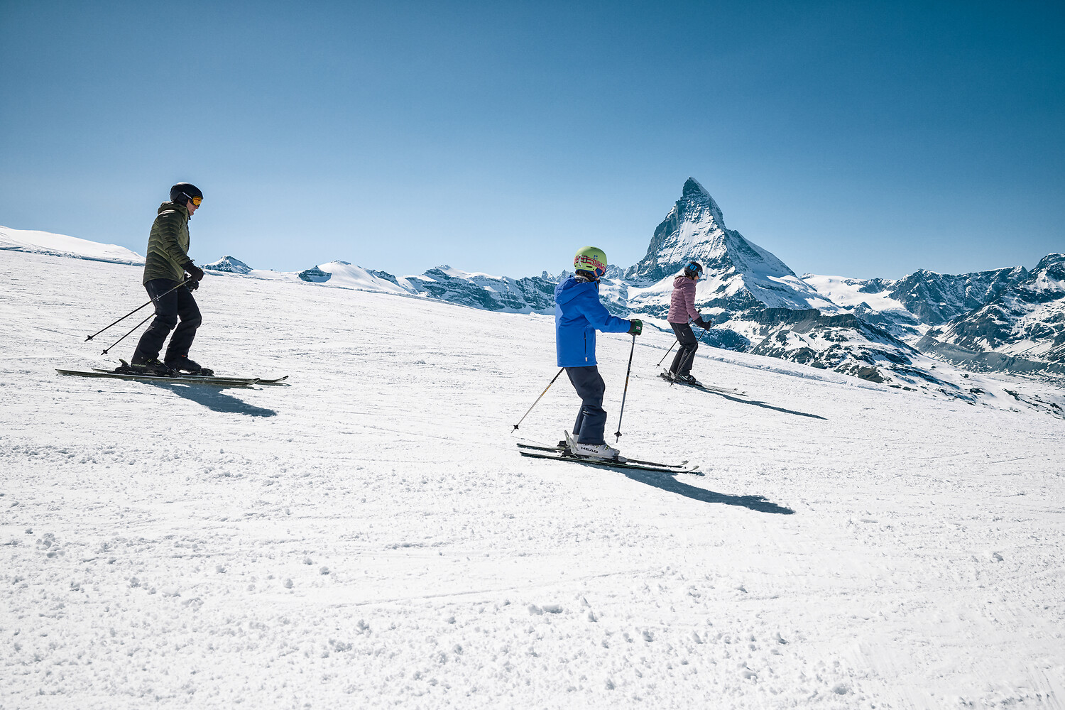 Skiers on a sunlit run with the Matterhorn behind them
